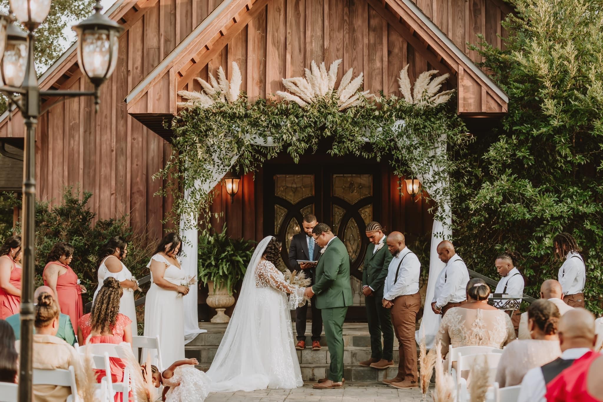 A couple getting married under an arch of greenery.