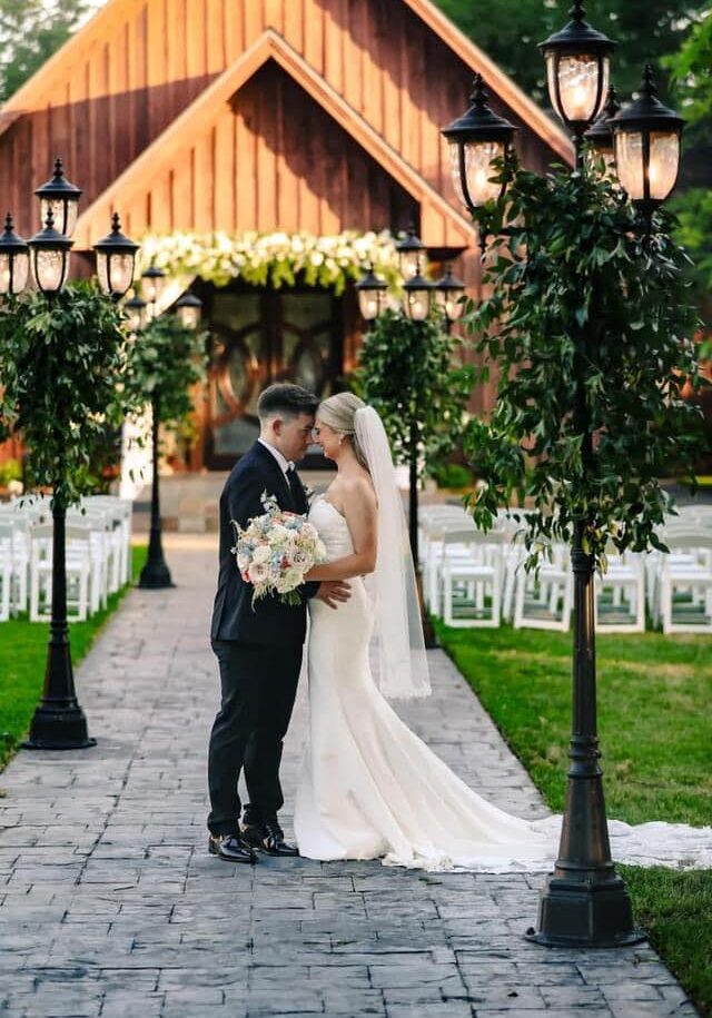 Bride and groom pose in front of a barn.